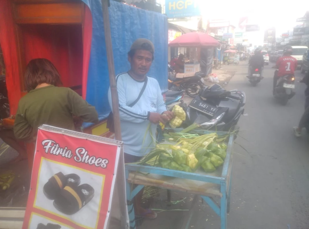 Dayat seorang penjual ketupat lebaran di pusat pertokoan Jalan Pamanukan saat menjajakan dagangannya sambil terus melipat daun janur kuning membentuk ketupat, Senin (8/4). (Dadan Ramdan/Pasundan Ekspres)