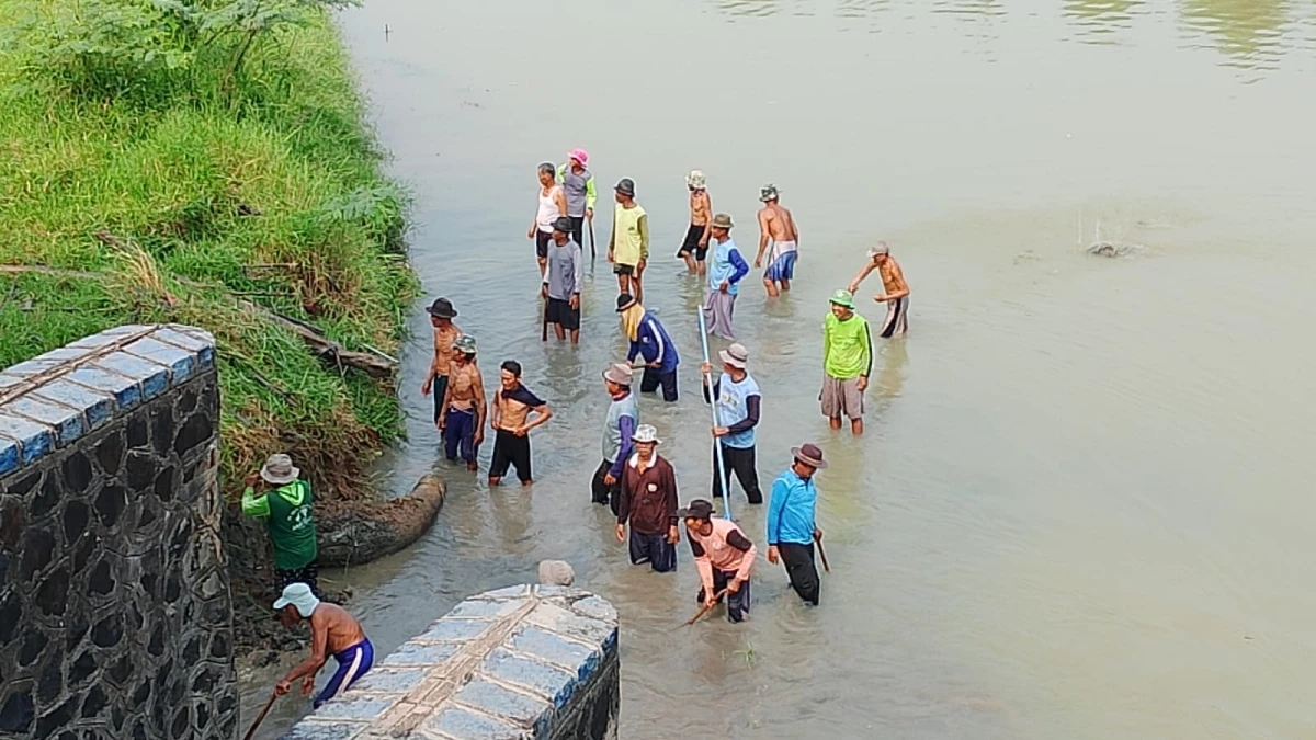 KEBOCORAN PINTU AIR: Petani Desa Nanggerang Kecamatan Binong turun  ke saluran bangunan pintu air yang bocor, berupaya menutupinya dengan alat sederhana, Jumat (24/5).