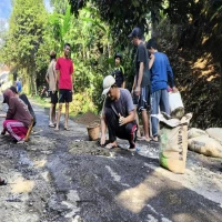 Warga RW 01 dan RW 02 secara sukarela melakukan aksi tambal jalan berlubang di jalan Kampung Cipatat Desa Pasanggrahan pada Minggu (13/7/2025). (Hadi Martadinata/Pasundan Ekspres)